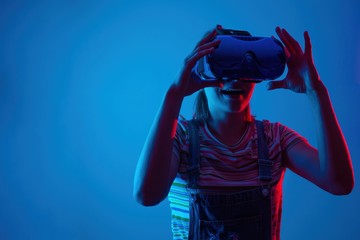 The game vr.The girl in the helmet and with the controller plays a game with creative light.