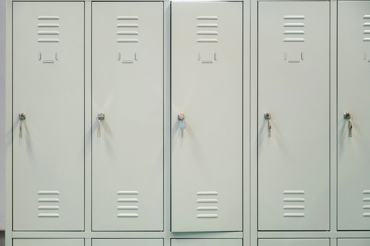 A row of grey metal school lockers with keys in the doors