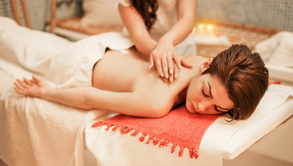 Obraz na płótnie Canvas Young woman having back therapy massage in spa resort hotel salon - Female enjoying relaxing thai massage - Body care, skin care, wellness and chilling concept - Focus her eye