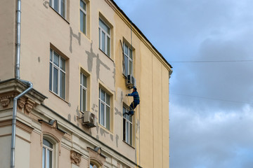 Fototapeta na wymiar MOSCOW - OCTOBER 27, 2018: A working painter - a mountaineer is painting a residential building