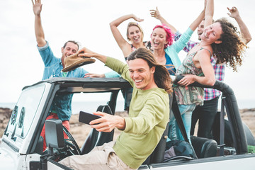 Group of happy friends doing excursion on desert in convertible 4x4 car - Young people having fun...