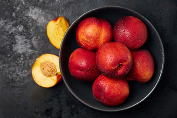 Fresh ripe nectarines on black rustic wooden background. Top view with copy space