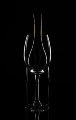 Wine bottle behind the wine glass, isolated on black