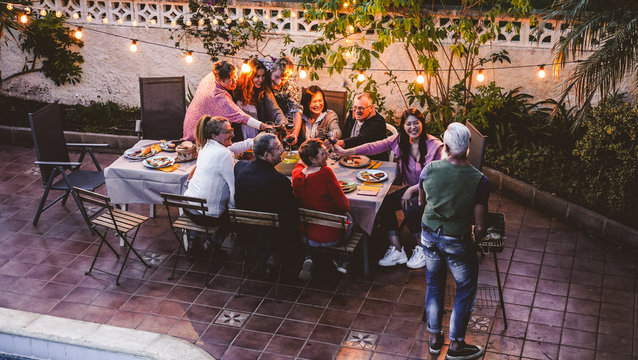 Happy family eating and cheering with red wine at barbecue party dinner - Different age of people having fun at bbq meal sitting in villa backyard - Summer lifestyle and food concept - Focus on faces