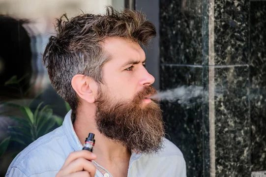 Bearded brutal male smoking electronic cigarette. Mature hipster with beard.  hipster man hold vaping device. man smoking ecigarette. Health safety and  addiction. inhaling vapor. Lighting up cigarette Stock Photo | Adobe Stock