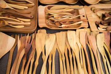 Close up of wooden utensils for the kitchen, bowls, spoons, forks on dark background. Concept of natural dishes, a healthy lifestyle. Texture of wood. Wooden eco-ware