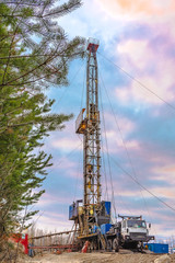 Drilling a deep well mobile drilling rig in an oil and gas field. The field is located in the Far North in the taiga. Beautiful dramatic sunset sky in the background.
