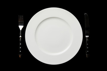 top view of white empty round plate and knife with fork isolated on black