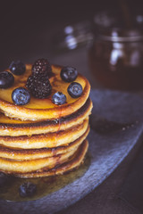 American Pancakes with Organic Berries and Maple Syrup on Dark Background. Classic Homemade Breakfast.