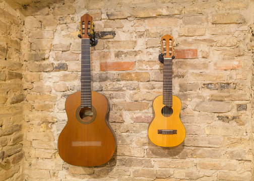 Two acoustic guitars hanging on brick wall background indoors. V © CrispyMedia