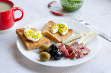 Simple breakfast on white background. Eggs, toast, olive, salami, cheese