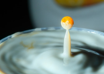 high speed photograph of a caramel milk drop on dark background