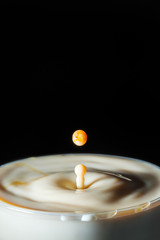 high speed photograph of a caramel milk drop on black background