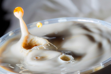 high speed photograph of a caramel milk drop on dark background