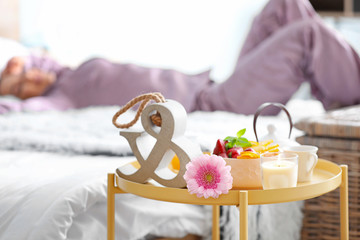 Table with tasty breakfast in bedroom of young woman