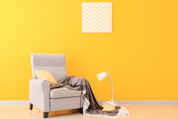 Cozy armchair near color wall in interior of living room