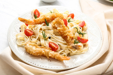Plate with tasty shrimps and pasta on table