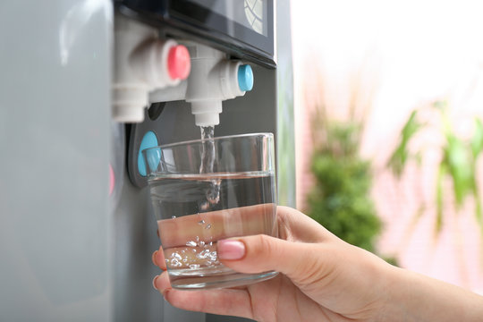 Woman Pouring Water From Cooler Into Glass