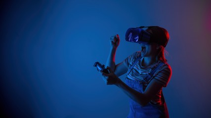 Fototapeta na wymiar The game vr. The girl in the helmet and the controller plays a game with creative light. concept of cyber sports. games. viral reality