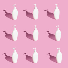  A lot of white bottles with dispenser on a pink background. Hard light, hard shadows.