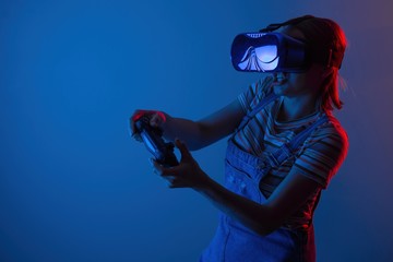 Naklejka premium The game vr. The girl in the helmet and the controller plays a game with creative light. concept of cyber sports. games. viral reality