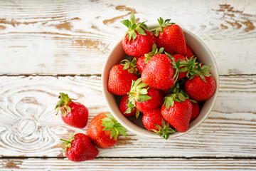 Bowl with ripe red strawberry on wooden background