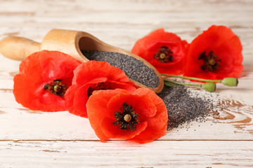 Beautiful red poppy flowers and scoop with seeds on wooden background