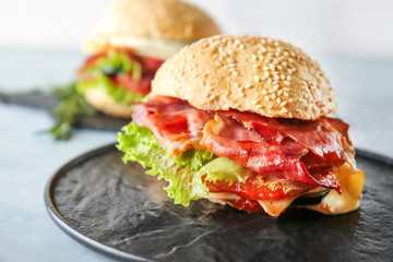 Tasty burger with bacon on table