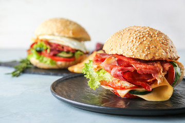 Tasty burgers with bacon on table