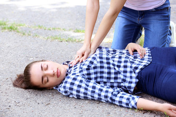 Female passer-by doing CPR on unconscious woman outdoors