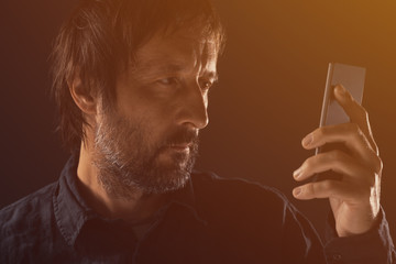 Adult man looking at mobile phone screen