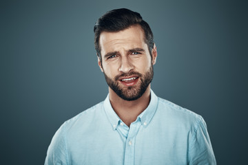 Charming man. Handsome young man looking at camera while standing against grey background
