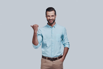 Solution is here. Handsome young man pointing copy space and looking at camera while standing...