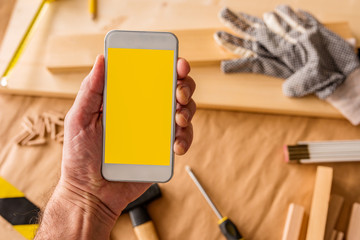 Small business woodwork entrepreneur holding smartphone with mock up screen