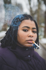 portrait of young african woman smoking cigarette and looking camera
