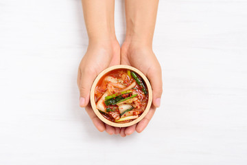 Kimchi cabbage in a bowl holding by hand on white background, Korean food, top view