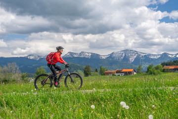 senior woman riding an electric mountain bike in early springtime in the Allgau area, a part of the Bavarian alps, Germany