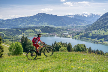 senior woman riding her electric mountain bike in springtimeon the mountains above the Alpsee near Immenstadt, Allgau,Bavaria, Germany