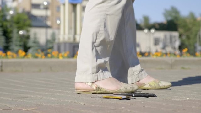 Closeup phone falls and breaks into pieces on road. girl drops smartphone on track in park.