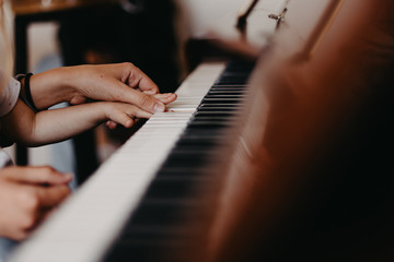 Cute little happy child girl playing piano in a light room. Selective focus, noise effect © Максим Галінский