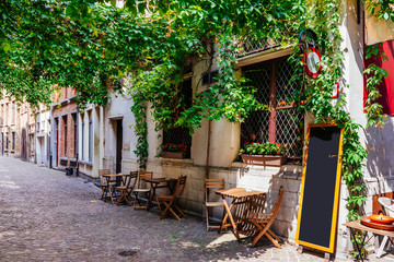 Fototapeta na wymiar Old street with table of cafe in historic city center of Antwerpen (Antwerp), Belgium. Cozy cityscape of Antwerp. Architecture and landmark of Antwerpen
