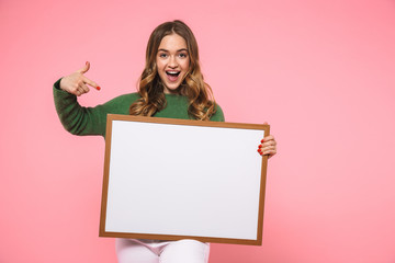 Cheerful blonde woman holding blank board and pointing on it