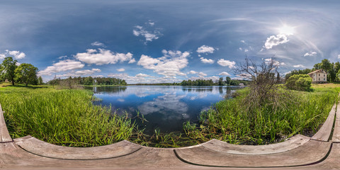 full seamless spherical hdri panorama 360 degrees  angle view on wooden pier of huge lake or river in sunny summer day and windy weather with beautiful clouds in equirectangular projection, VR content