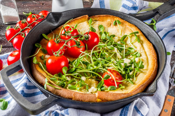 Savory vegan dutch baby baked pancake with salad leaves and vegetables, wooden background copy space