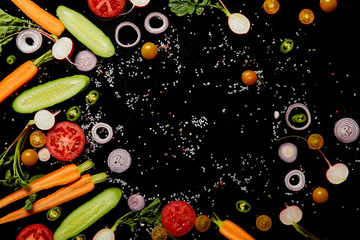 top view of fresh cut vegetables with salt isolated on black with copy space