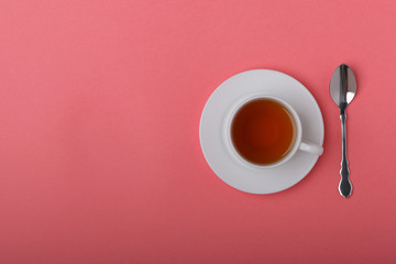 A white cup of tea on a pink background.
