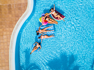 Coloured aerial background group of friends woman caucasian people enjoying the summer holiday vacation at the blue water pool with trendy inflatable mattress lilos together with fun and happiness