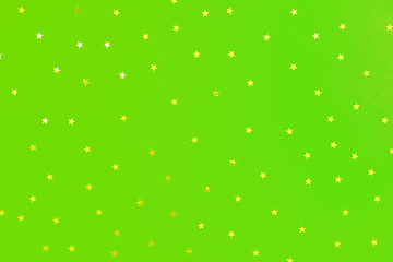 Holographic stars and gold sparkles on green background. Festive backdrop for your projects