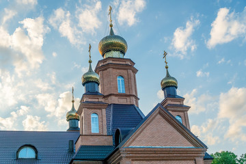 Fototapeta na wymiar Part of the Orthodox Church with four domes and crosses close-up against the blue sky. Orthodox cross