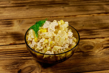 Festive salad with chicken breast, sweet corn, canned pineapple, cheese and mayonnaise on wooden table